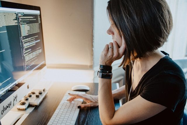 Frau sitzt am PC und programmiert einen Code