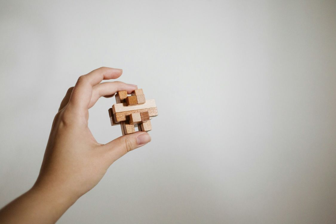 Hand h&auml;lt ein Holzpuzzle in die H&ouml;he