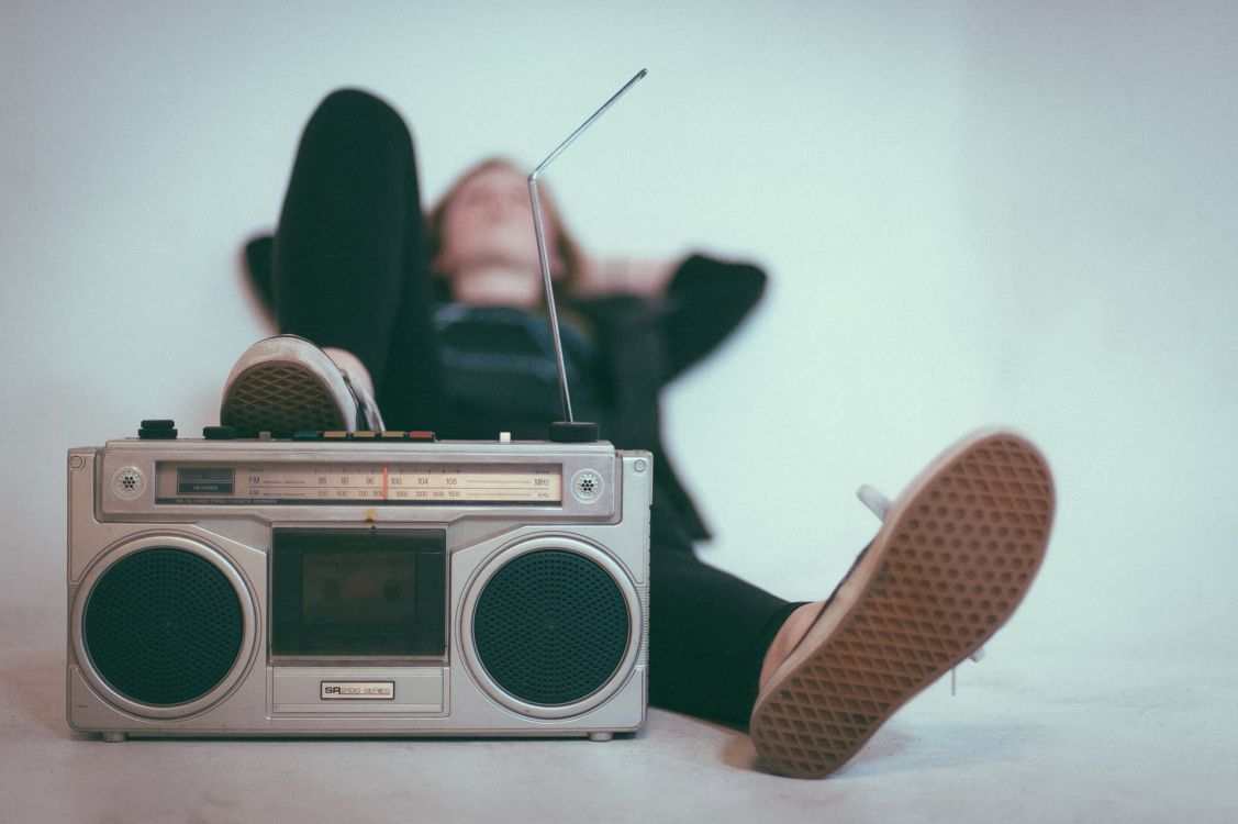 Mensch liegt auf dem Rücken hinter einem alten Radiogerät