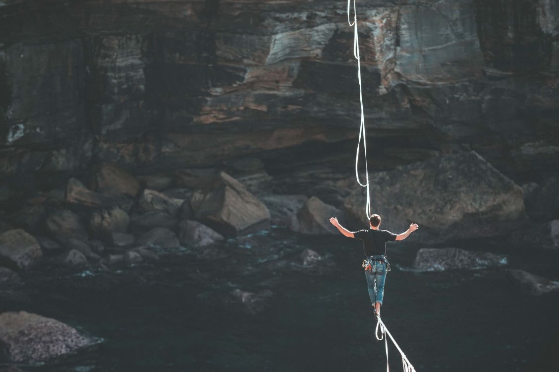 Mann, der auf einem d&uuml;nnen Seil &uuml;ber eine Schlucht balanciert