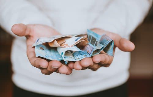 zwei Handfl&auml;chen, die zu einer Schale geformt sind und Geldscheine beinhalten