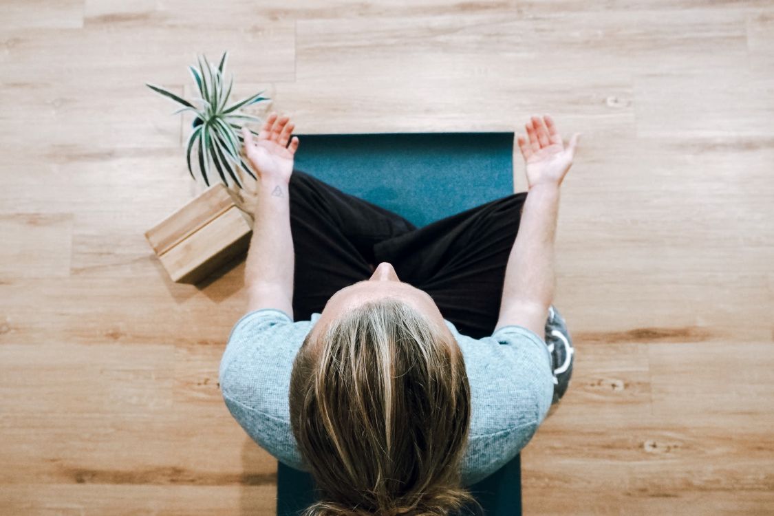 Frau im Schneidersitz auf dem Boden in Meditationshaltung
