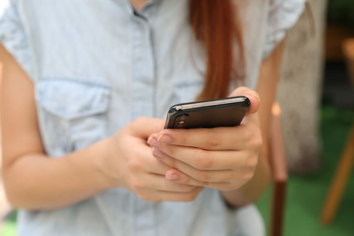 Frau h&auml;lt Smartphone in beiden H&auml;nden