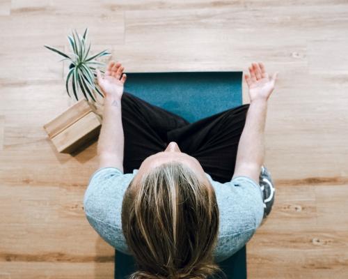 Frau im Schneidersitz auf dem Boden in Meditationshaltung